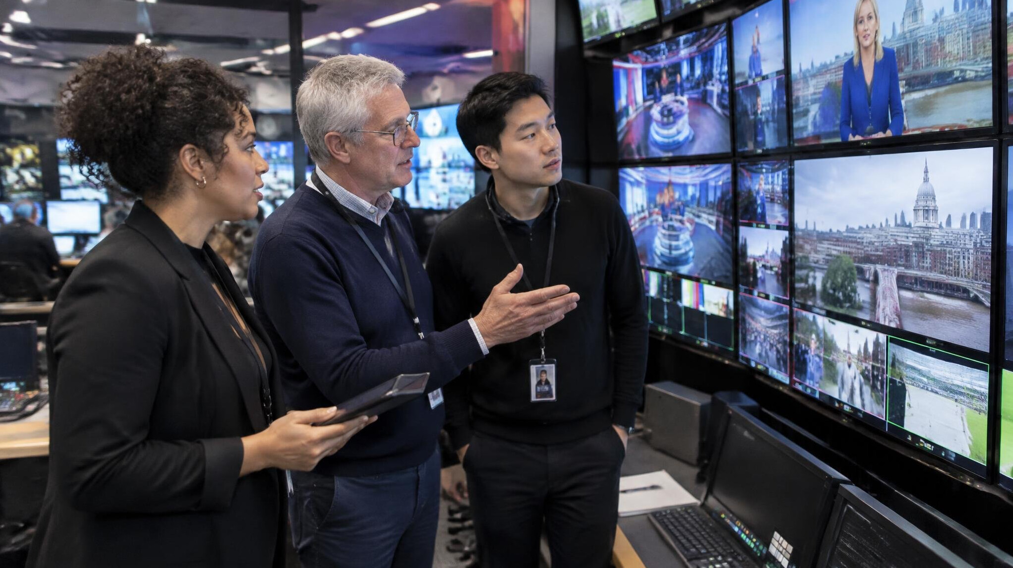 Broadcast engineers collaborating around a studio monitor wall